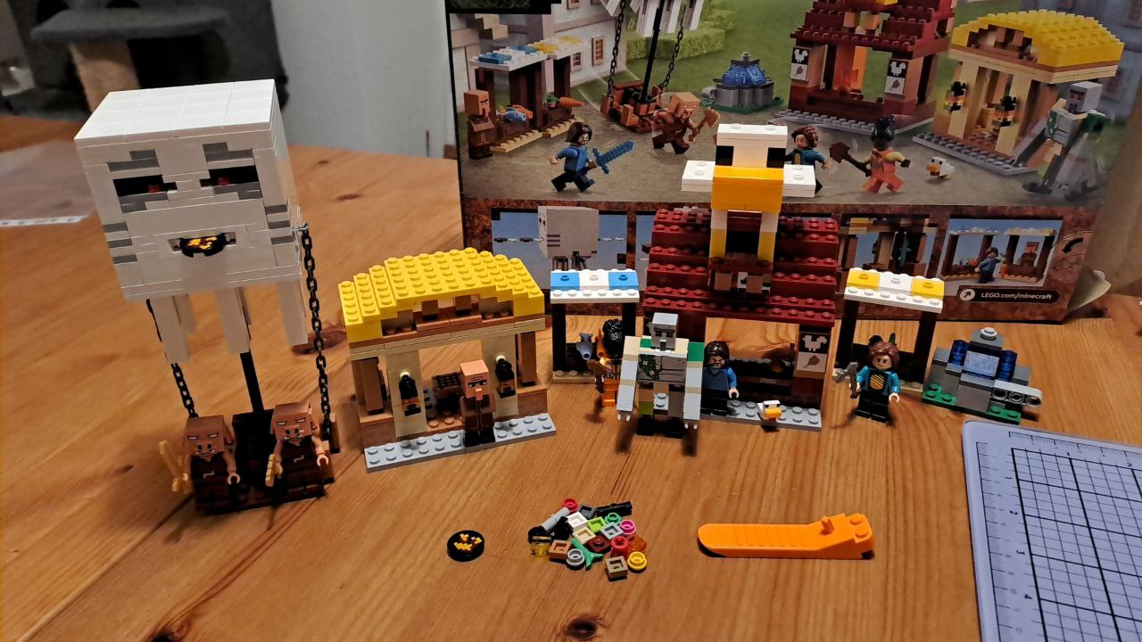 A minecraft lego set 21273. A couple of booths, 2 larger buildings probably also stores of sorts. A villager minifig. 2 piglin minifigs. 3 'players' which are regular minifigs. A golem. A.. uh.. chicken. Yeah, a chicken minifig of sorts. A ghast hot air balloon, it's the coolest structure of the bunch. It can actually shoot fireballs! A uh... 'catapult' though it sucks. Probably from the movie, haven't seen the movie. A bunch of pixelated 'tools'. Yeah, overall a pretty amusing build. There's even a crafting table in the straw-roofed hut. I'm only missing a red poppy for the golem, missed opportunity there!